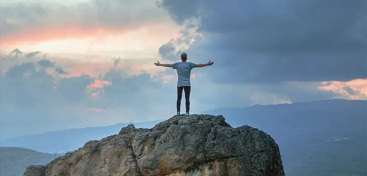 Man standing on a cliff with arms wide open